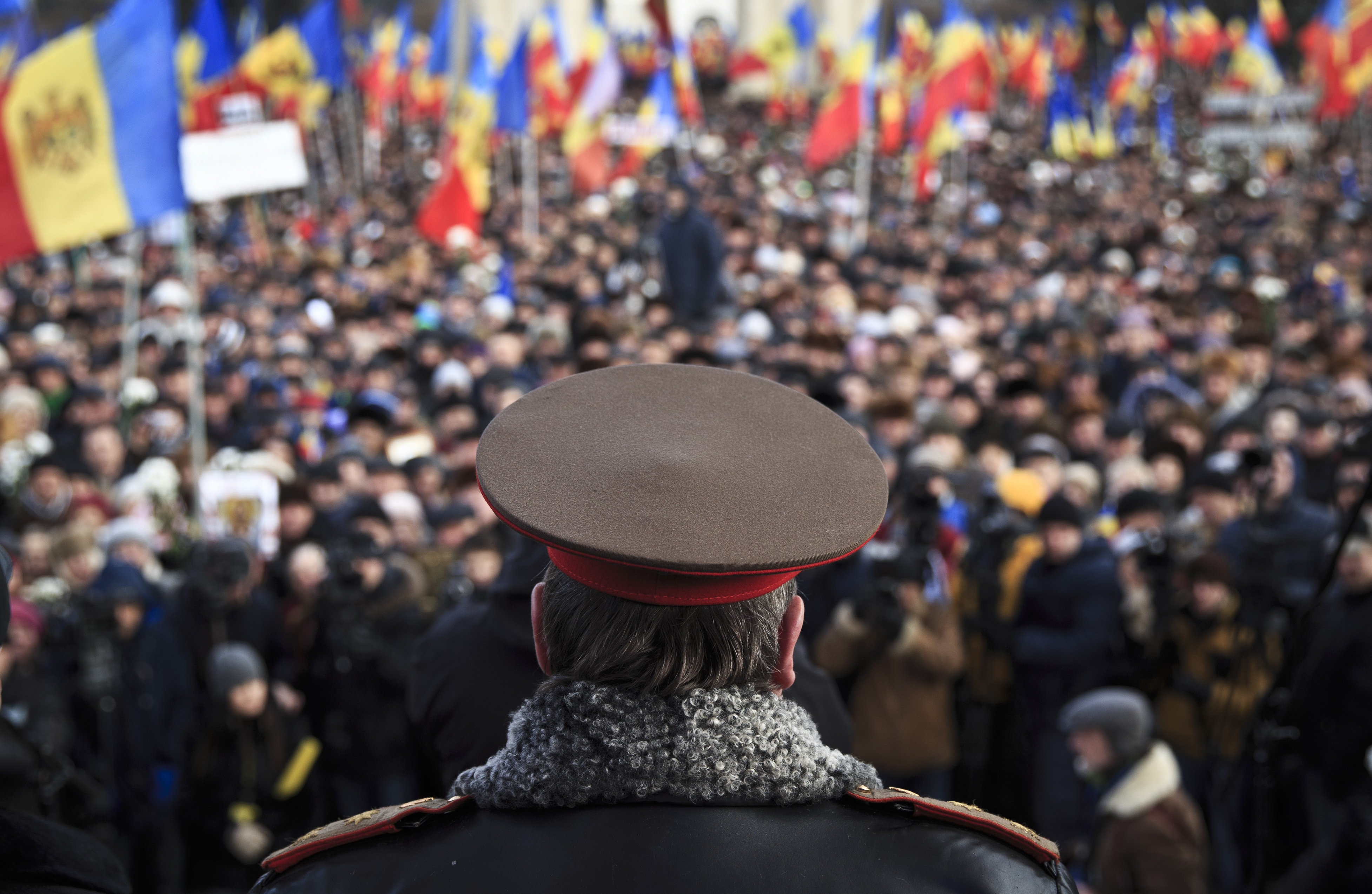A Moldovan army general watches demonstrators during a large protest in Chisinau, Moldova, Sunday, Jan. 24, 2016