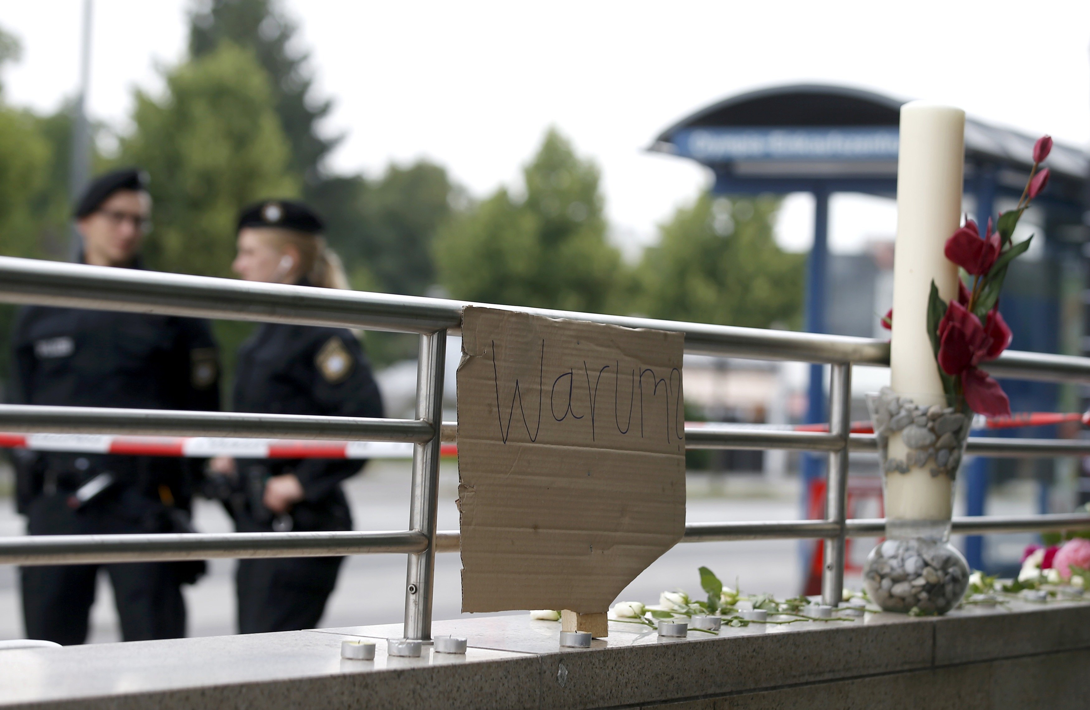 A sign reading 'Why' and flowers are placed on on a wall near the Olympia shopping mall, where yesterday's shooting rampage started, in Munich, Germany July 23, 2016.
