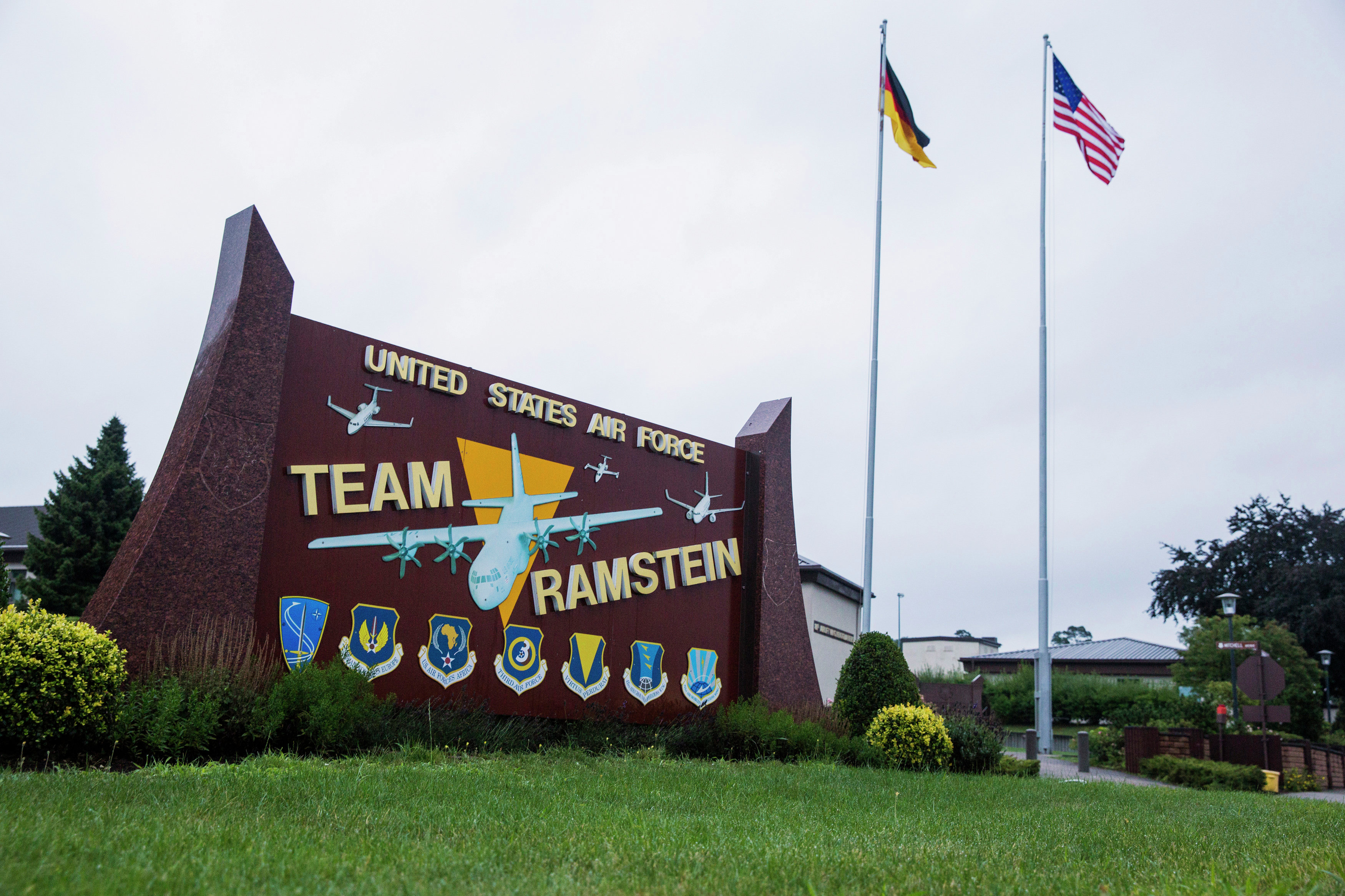 The flags of the United States and Germany fly behind a sign at Ramstein Air Base, Germany.